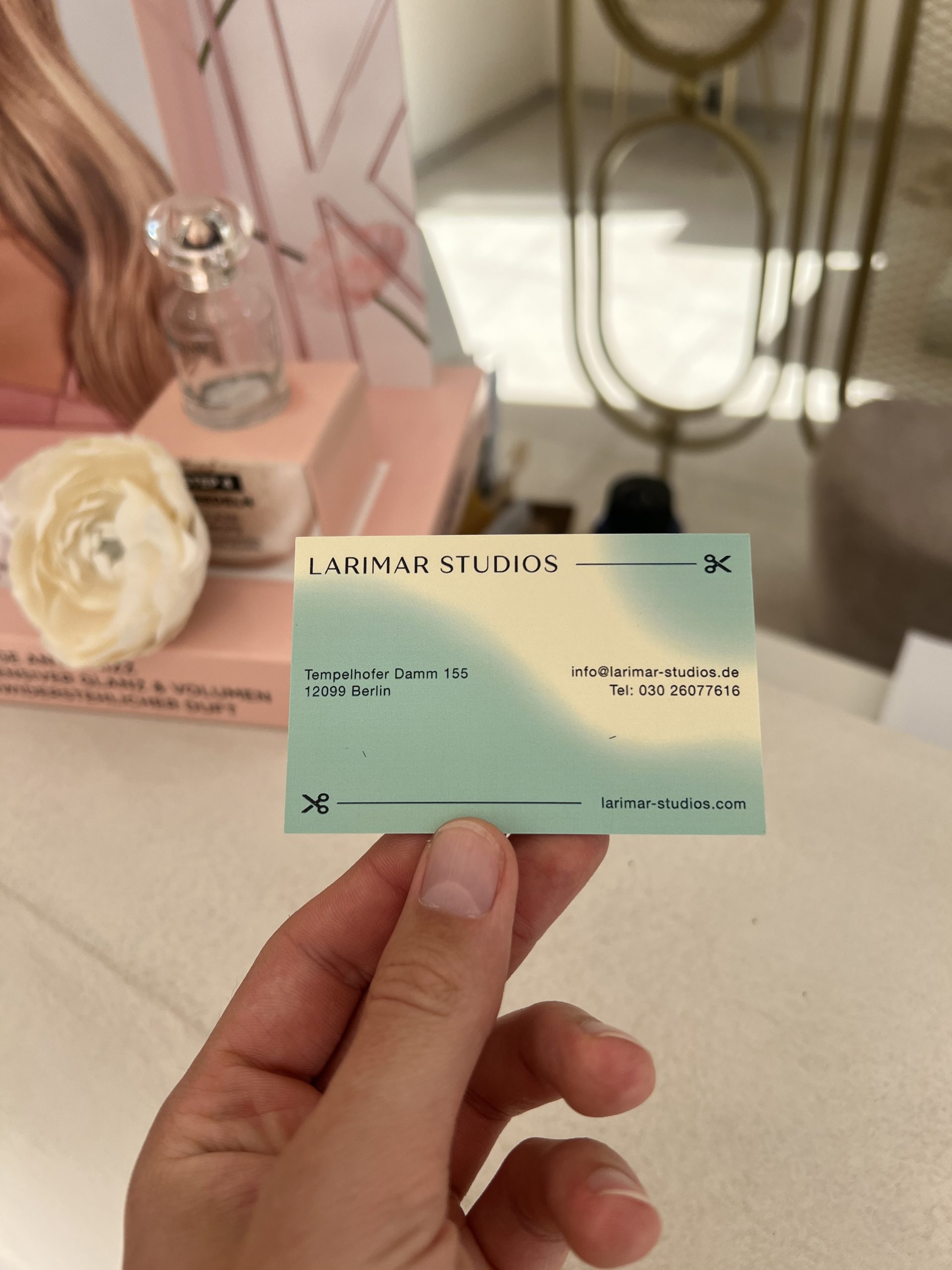 Rückseite der Larimar Studios Visitenkarte mit Adresse und Kontaktdaten in der Hand